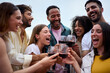 © CarlosBarquero - Portrait of multi-ethnic laughing young people toasting glasses red wine outdoor. Gathering of millennial friends together celebrating a party enjoying leisure time on summer holidays