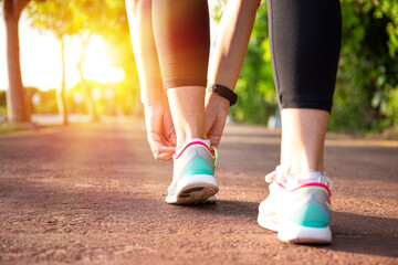 Runner woman tying up laces of shoes, getting ready to run for cardio and weight loss