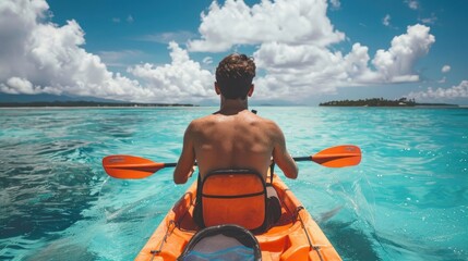 Young man in an orange kayak on the turquoise ocean, tropical island background. Beautiful blue sky with clouds. View from behind