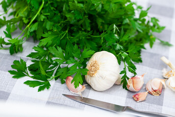 Wall Mural - Cutting board with fresh seasonings on a wooden background. White garlic heads and cloves and parsley leaves. Condiments