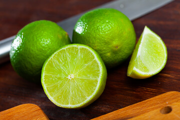 Wall Mural - Picture of cut fresh raw green limes on wooden table in home kitchen