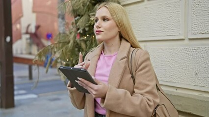 Poster - Blonde woman using tablet on city street, reflecting modern urban lifestyle and technology.