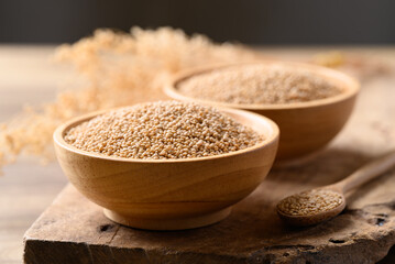 Wall Mural - Brown quinoa seed in bowl with spoon on wooden background, Healthy food ingredient