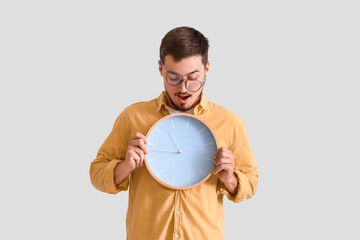 Canvas Print - Stressed young man with clock on light background. Deadline concept