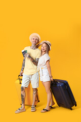 Wall Mural - Young couple with passports and suitcases on yellow background