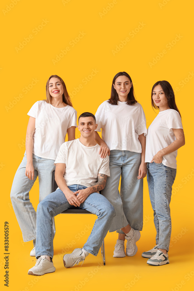 Group of young people in stylish jeans on yellow background