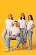 © Pixel-Shot - Group of young people in stylish jeans on yellow background