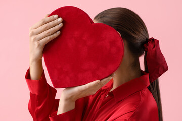 Poster - Beautiful young woman with ponytail and scrunchy holding heart on pink background