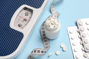 Wall Mural - Bottle with weight loss pills, scales and measuring tape on blue background