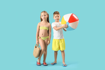 Wall Mural - Cute little children with wicker bag and beach ball on blue background
