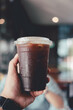 © Dontree - Man hand holding a take-out iced americano, a glass refreshment.