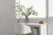 © Pixel-Shot - Vase with blooming branches on workplace in white room