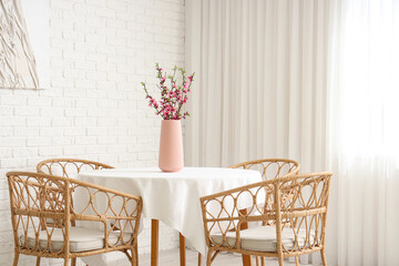 Wall Mural - Vase with blooming Sakura branches on table near armchairs in dining room