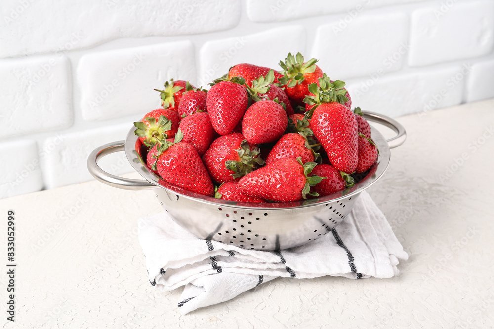 Colander with sweet fresh strawberries on white table
