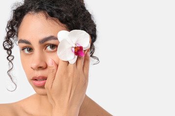 Poster - Beautiful young African-American woman with orchid flower on white background