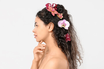 Poster - Beautiful young African-American woman with orchid flowers in her hair on white background