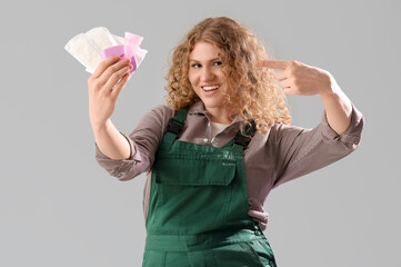 Wall Mural - Female worker pointing at feminine hygiene items on grey background