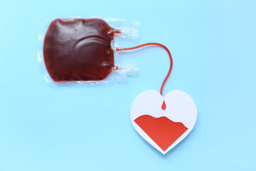 Wall Mural - Blood pack with paper heart on blue background. World Blood Donor Day
