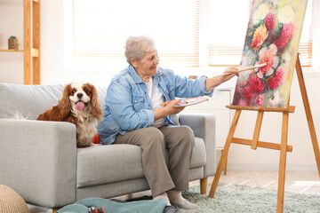 Sticker - Senior woman with cute cavalier King Charles spaniel dog painting at home