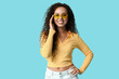 © Pixel-Shot - Happy young African-American woman in sunglasses on blue background
