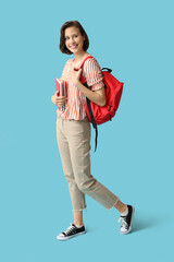 Wall Mural - Happy female student with backpack and notebooks on blue background