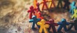 © nattapon98 - Colorful paper cutout figures holding hands in a circle on a wooden surface, symbolizing unity, teamwork, and diversity.