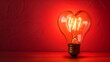 © Borneo - Light bulb with a heart shape glowing filament on a red background