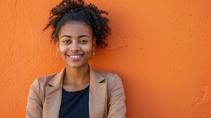 Wall Mural - Young professional woman with a confident smile, standing against a vibrant orange wall