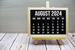 © may1985 - August 2024 monthly calendar on easel stand on wooden background