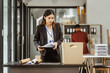 © M+Isolation+Photo - A young Asian businesswoman in a formal suit is working at her desk, preparing to resign after being laid off. She carefully drafts her resignation letter and plans her next steps.