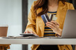 © M+Isolation+Photo - A young woman and other Asian individuals in formal suits are seen working at desks with laptops, possibly engaged in activities like online shopping using credit cards.