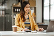 © M+Isolation+Photo - A young woman and other Asian individuals in formal suits are seen working at desks with laptops, portraying a successful and happy demeanor.