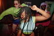© Seventyfour - Dynamic high angle shot of multiethnic group of young people dancing with camera flash trendy Black young woman in foreground