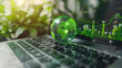 © Khajornyot - On the keyboard of the laptop, there is a green globe with stock graphs displayed on the laptop screen. This is a green business concept. Carbon efficient technology. Digital sustainability.