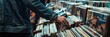 © Ilia Nesolenyi - Person holding a stack of vinyl records while browsing in a record store