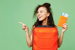 © ViDi Studio - Traveler woman in yellow casual clothes hold bag passport ticket point aside isolated on plain green background. Tourist travel abroad in free spare time rest getaway Air flight trip journey concept