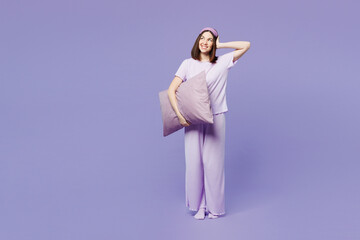 Wall Mural - Full body young happy calm woman wear pyjamas jam sleep eye mask rest relax at home hold pillow look aside on area isolated on plain pastel light purple background studio. Good mood night nap concept.