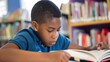© Felippe Lopes - Focused young boy reading a book in a library, surrounded by books on a sunny day, depicting education and concentration.