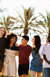 © Xavier Lorenzo - Vertical photo of young group of happy diverse friends laughing while enjoying summer vacation walking together in the beach