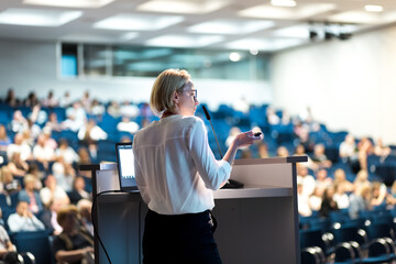 Wall Mural - Female speaker giving a talk on corporate business conference. Unrecognizable people in audience at conference hall. Business and Entrepreneurship event