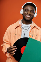 Wall Mural - Stylish young African American man holding a record and wearing headphones.