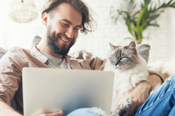 Wall Mural - Smiling man with a cat using a laptop.