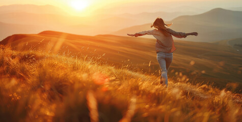 Canvas Print - A woman is running on the grassy hill, with her arms outstretched and smiling as she looks at the sun setting behind her in warm tones.