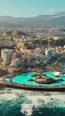 Wall Mural - Aerial view of Puerto de la Cruz cityscape at sunrise, Tenerife, Spain. Purto de la Cruz town with Teide volcano at background on Tenerife, Canary islands. Swimming pool complex and waterfront