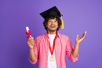 Wall Mural - Photo of nice young man mortarboard diploma look up empty space wear pink shirt isolated on violet color background