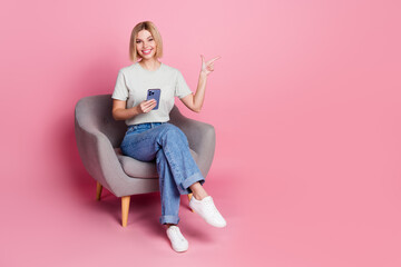 Poster - Photo of pretty adorable girl wear stylish grey clothes sit comfy chair empty space isolated on pink color background