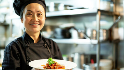 Wall Mural - Middle-aged Asian woman in a cozy kitchen, holding a colorful bowl of fruits and smiling warmly. Bright kitchen