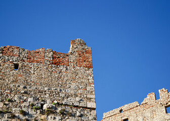 Wall Mural - An old stone wall of an ancient fortress against a background of clear blue sky.