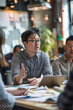 © wolfhound911 - an East Asian entrepreneur leading a product development meeting with colleagues in a creative workspace