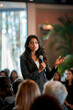 © wolfhound911 - an Indian businesswoman giving a keynote speech at a corporate event with an engaged audience